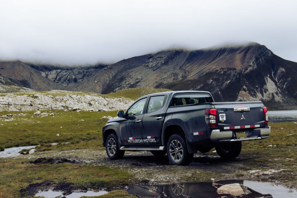 Mitsubishi Triton pickup truck parked in a scenic mountain landscape, showcasing off-road capabilities.